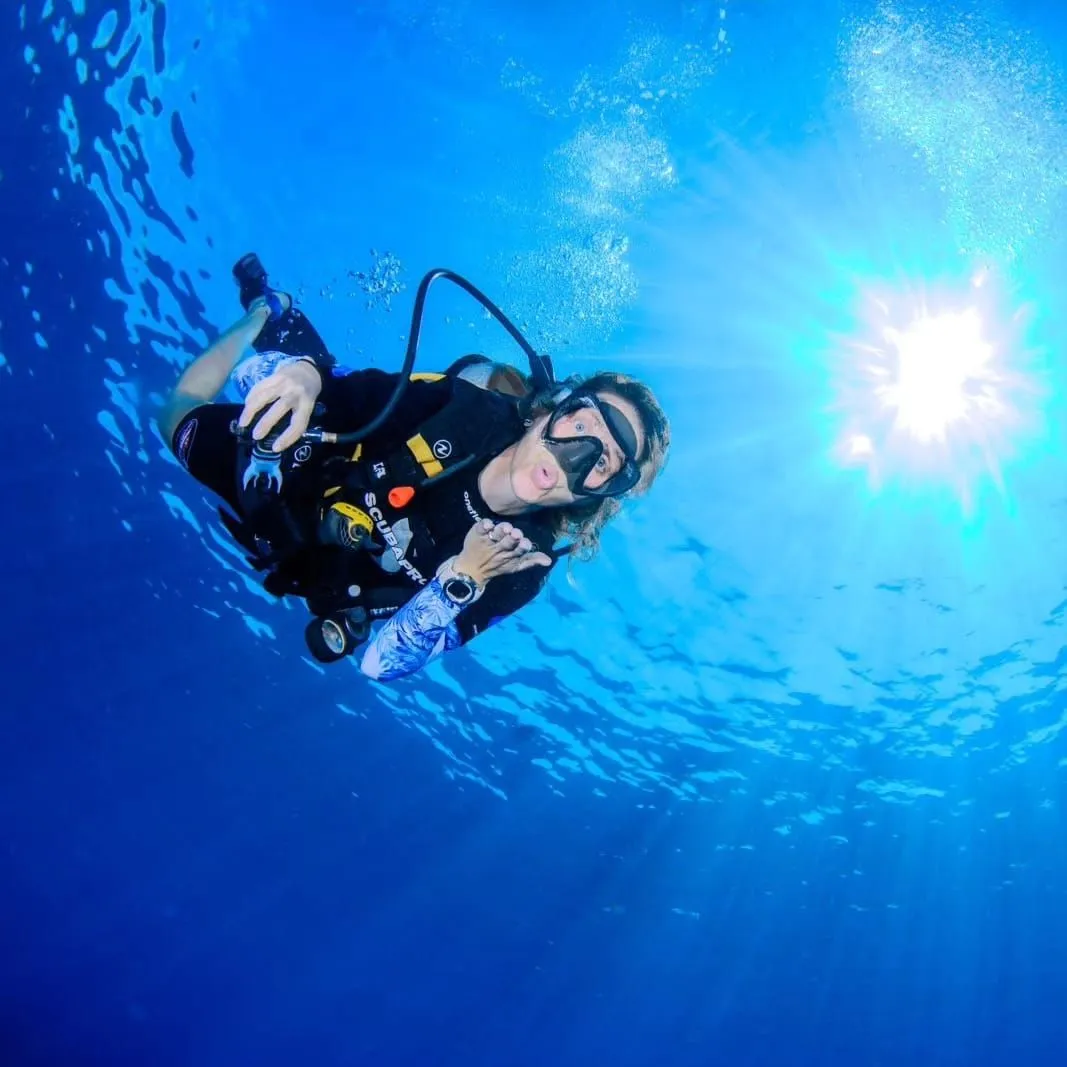 Diver above wreck with sunburst