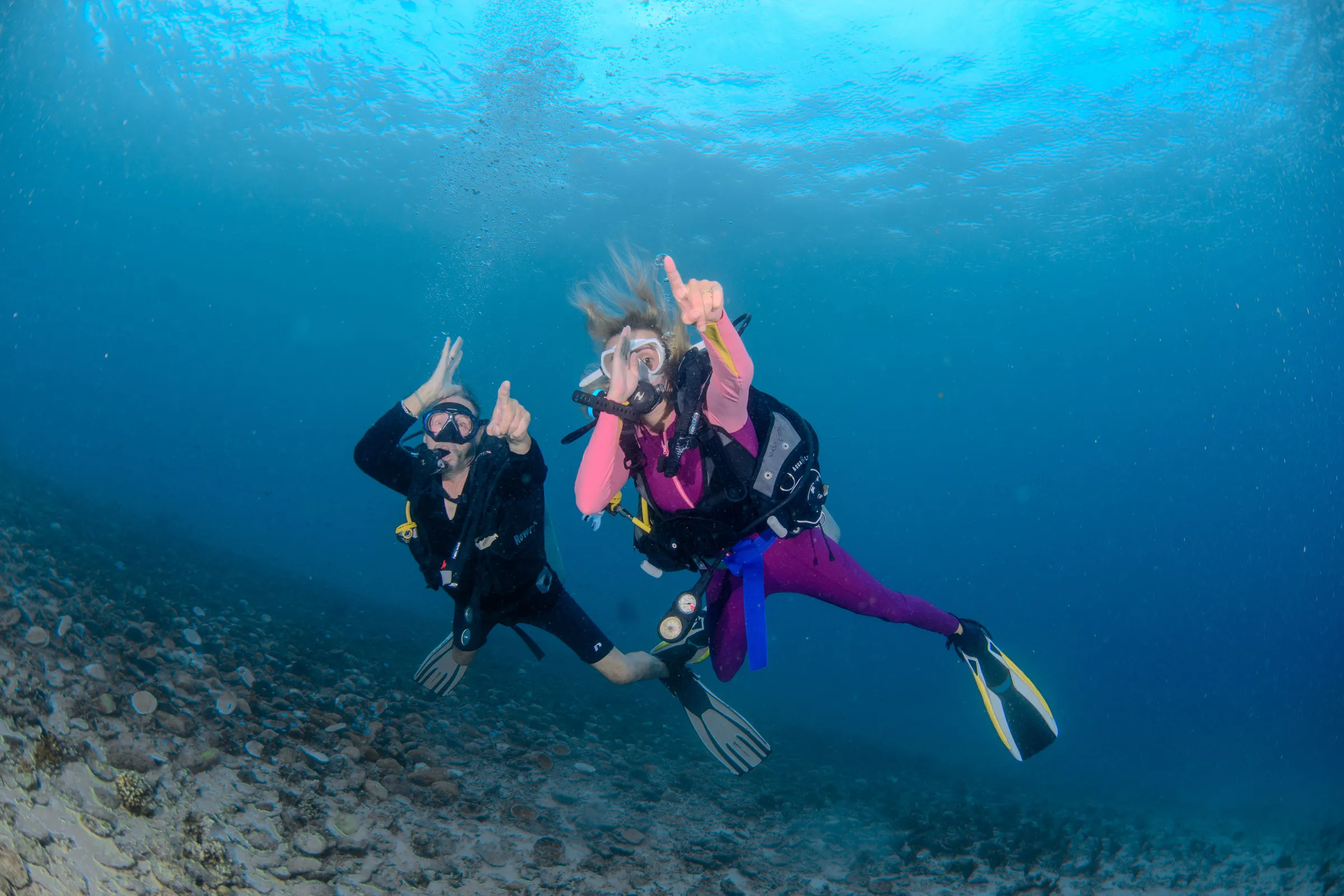 Buddy pair posing in pink wetsuits